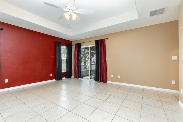 unfurnished room featuring a tray ceiling, ceiling fan, and light tile patterned flooring