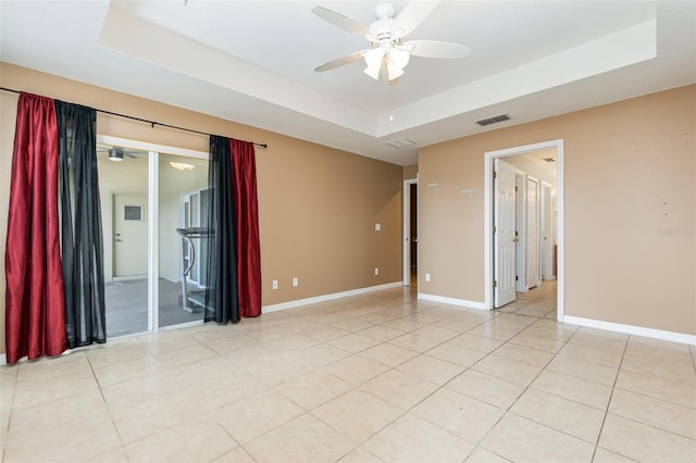 unfurnished room with a tray ceiling, ceiling fan, and light tile patterned floors