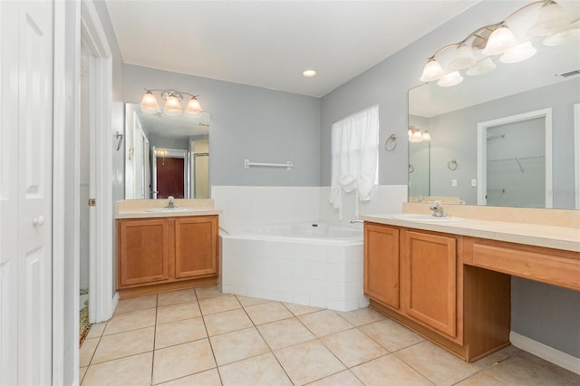 bathroom with tile patterned flooring, tiled tub, and vanity