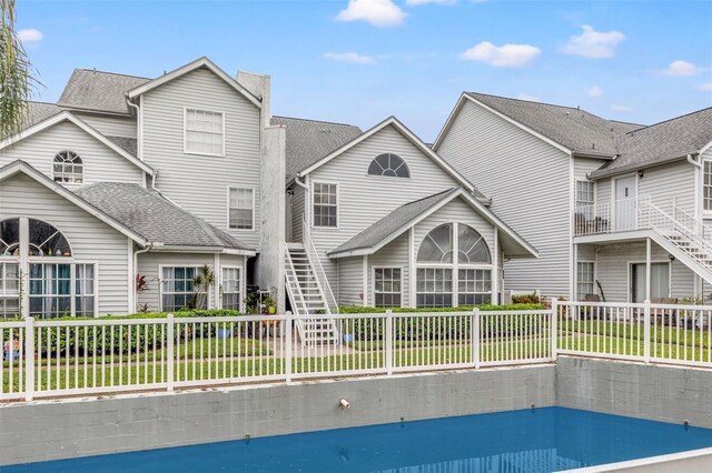 rear view of house with a yard, a sunroom, and a fenced in pool