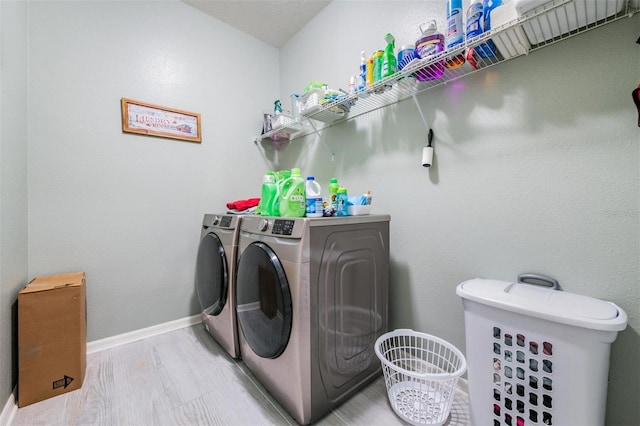 washroom with washer and clothes dryer and light wood-type flooring