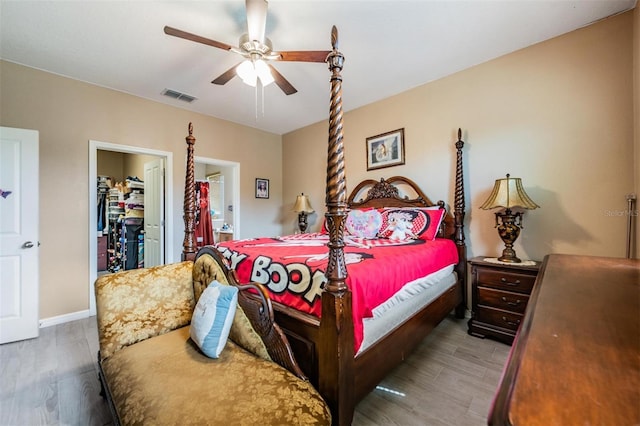 bedroom featuring hardwood / wood-style floors, a walk in closet, a closet, and ceiling fan