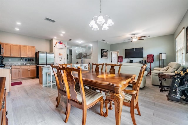 dining area with light hardwood / wood-style floors, sink, and ceiling fan with notable chandelier