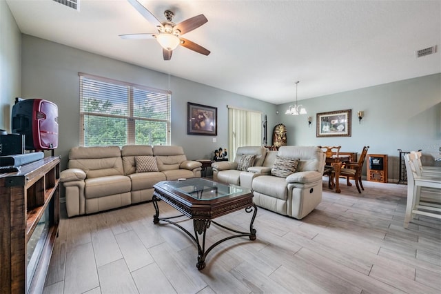 living room with light hardwood / wood-style floors and ceiling fan with notable chandelier