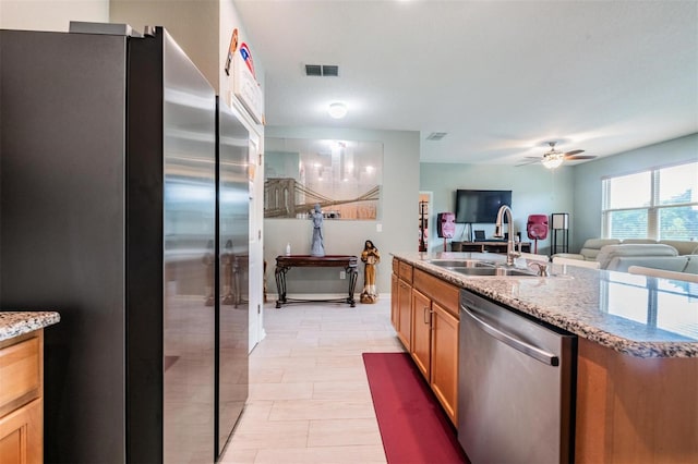 kitchen featuring sink, appliances with stainless steel finishes, light stone counters, and ceiling fan