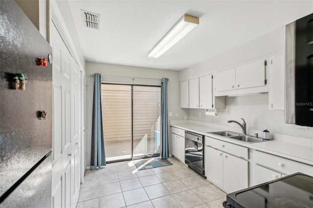 kitchen with black dishwasher, white cabinetry, stainless steel refrigerator, light tile patterned flooring, and sink