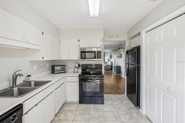 kitchen with light hardwood / wood-style flooring, white cabinets, black appliances, and sink