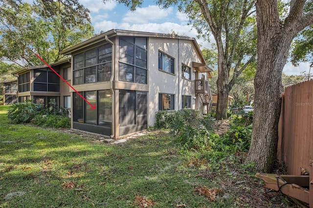 back of property with a lawn and a sunroom