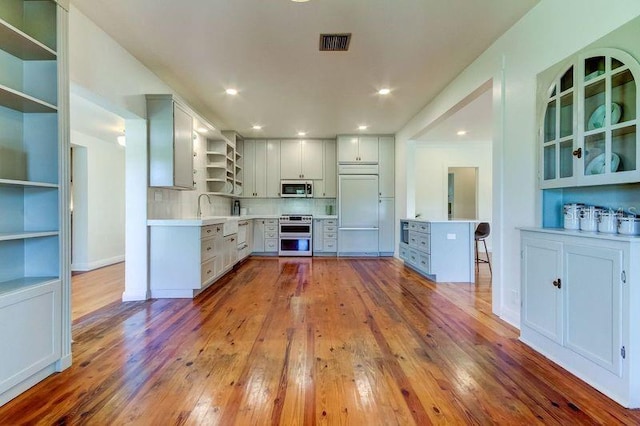 kitchen featuring backsplash, sink, light wood-type flooring, and appliances with stainless steel finishes