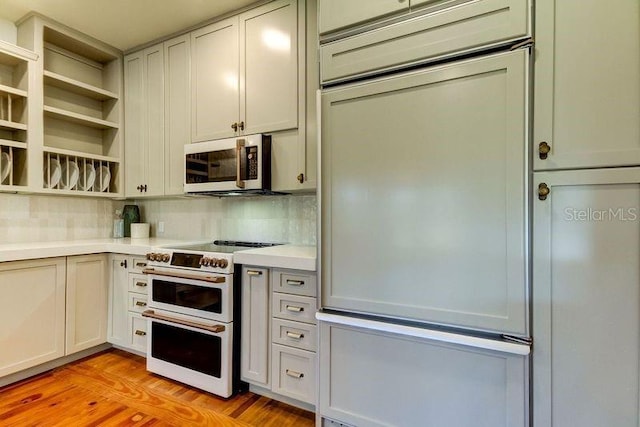 kitchen featuring tasteful backsplash, paneled built in fridge, white electric range oven, and light wood-type flooring