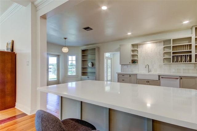 kitchen featuring dishwasher, sink, light wood-type flooring, tasteful backsplash, and decorative light fixtures