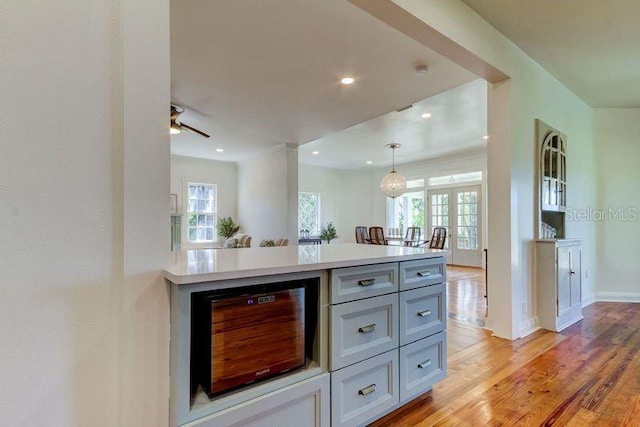 kitchen featuring light wood-type flooring, ceiling fan, pendant lighting, gray cabinets, and wine cooler