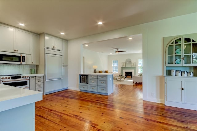 kitchen featuring electric range, ceiling fan, paneled refrigerator, light hardwood / wood-style flooring, and backsplash