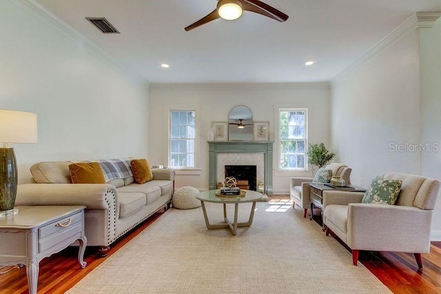 living room with hardwood / wood-style floors, ceiling fan, a premium fireplace, and ornamental molding