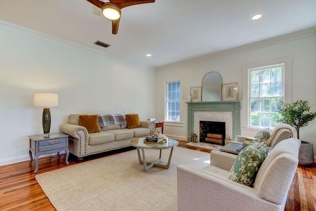 living room featuring hardwood / wood-style floors, ceiling fan, ornamental molding, and a premium fireplace