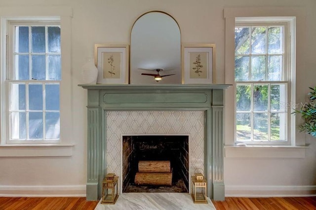 details with ceiling fan, wood-type flooring, and a tiled fireplace