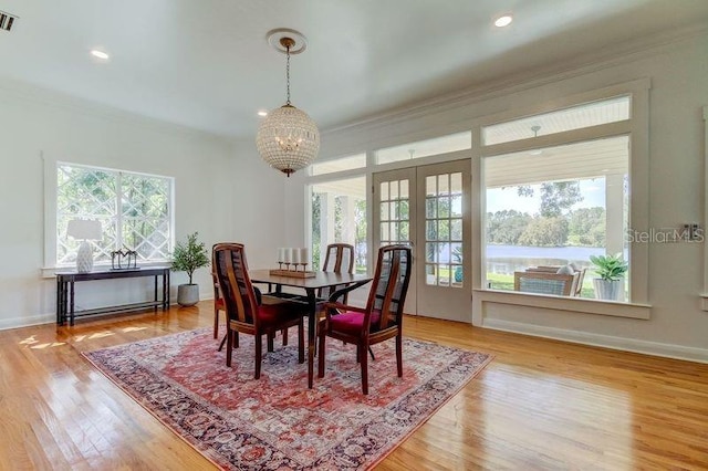 dining room featuring french doors, crown molding, and an inviting chandelier