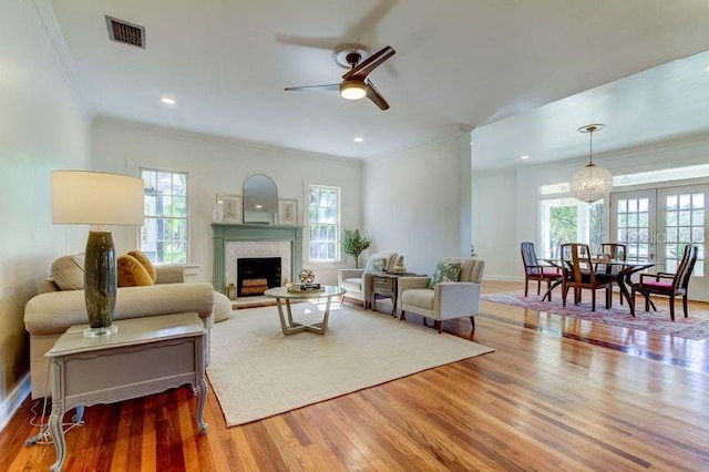 living room featuring wood-type flooring, ornamental molding, ceiling fan, and a healthy amount of sunlight