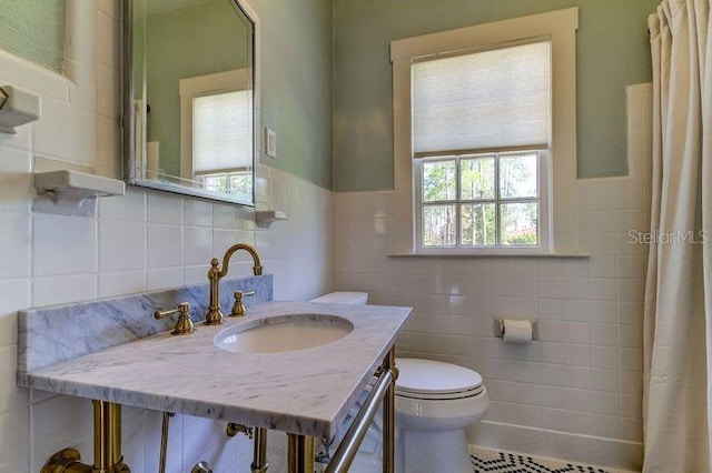 bathroom with tile patterned flooring, toilet, sink, and tile walls