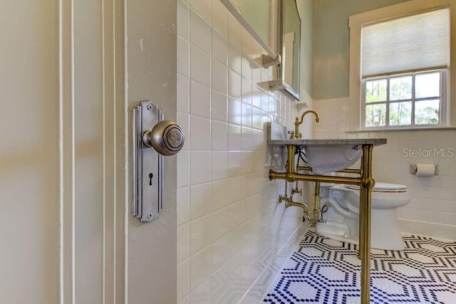 bathroom featuring toilet and tile walls