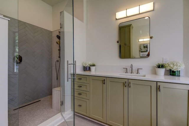 bathroom with tile patterned flooring, vanity, and tiled shower