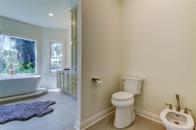 bathroom with tile patterned flooring, toilet, a tub to relax in, and a bidet