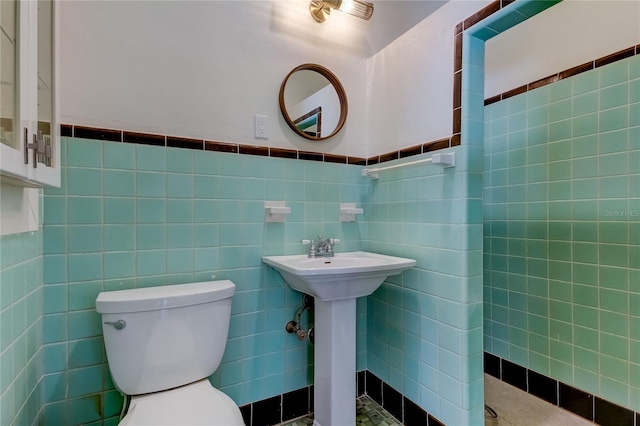 bathroom featuring toilet and tile walls