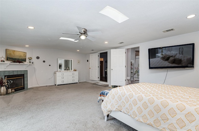 bedroom with carpet flooring, ceiling fan, a tile fireplace, and vaulted ceiling