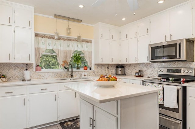 kitchen featuring white cabinets, sink, hanging light fixtures, a kitchen island, and stainless steel appliances