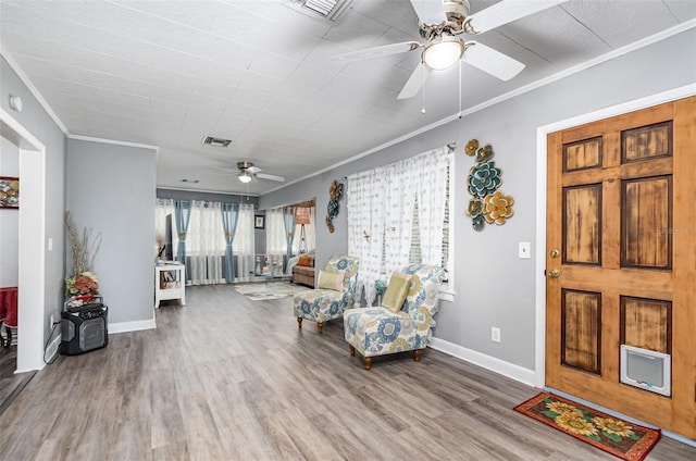 living room with ceiling fan, wood-type flooring, and ornamental molding