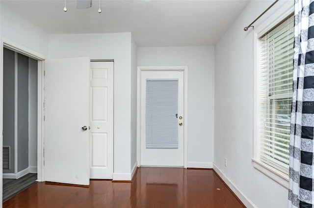 unfurnished bedroom featuring multiple windows and dark wood-type flooring