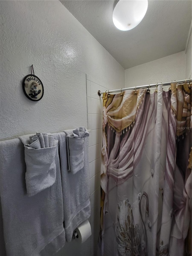 bathroom with curtained shower and a textured ceiling