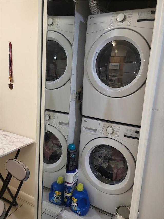 laundry room featuring light tile patterned floors and stacked washer and clothes dryer