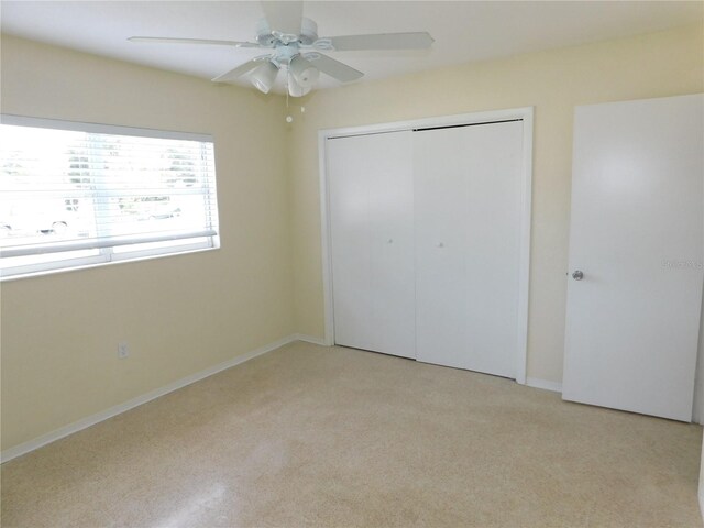 unfurnished bedroom featuring ceiling fan, a closet, and light colored carpet