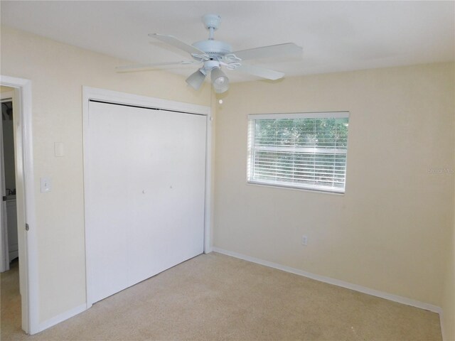 unfurnished bedroom with light carpet, ceiling fan, and a closet