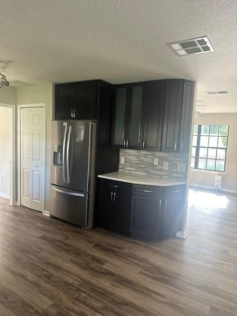 kitchen featuring a textured ceiling, stainless steel fridge with ice dispenser, dark hardwood / wood-style floors, and backsplash