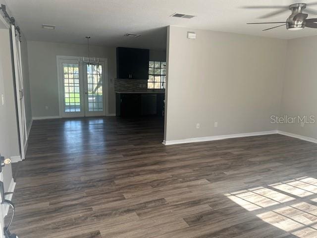 unfurnished room with dark hardwood / wood-style floors, a barn door, and ceiling fan