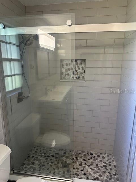 bathroom featuring toilet and a tile shower