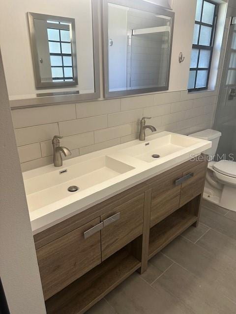 bathroom featuring tasteful backsplash, a shower with shower door, toilet, tile patterned floors, and vanity