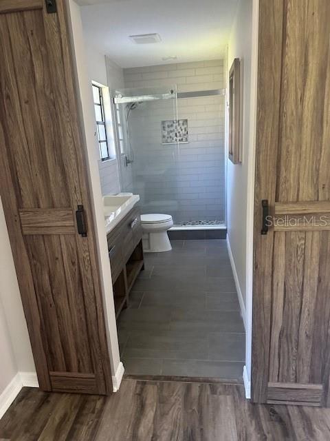 bathroom featuring vanity, hardwood / wood-style flooring, toilet, and walk in shower