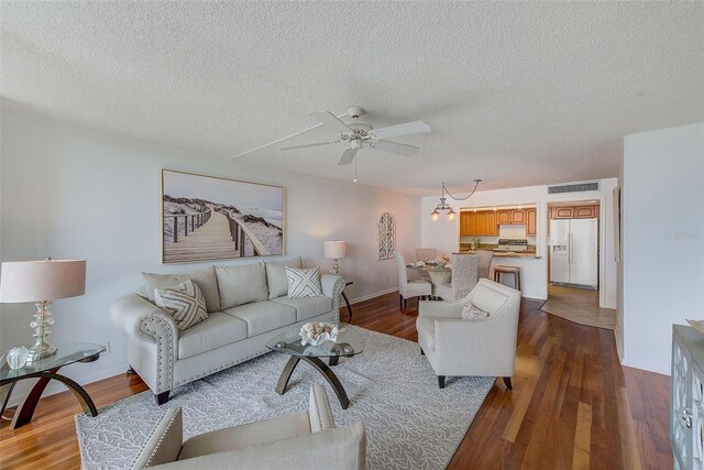 living room with ceiling fan with notable chandelier, hardwood / wood-style flooring, and a textured ceiling