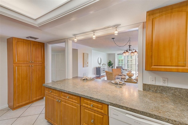 kitchen with light tile patterned floors, rail lighting, dishwasher, and a notable chandelier