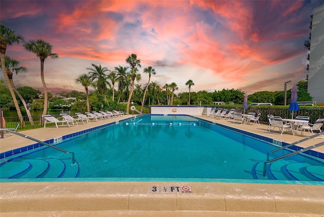 pool at dusk featuring a patio area