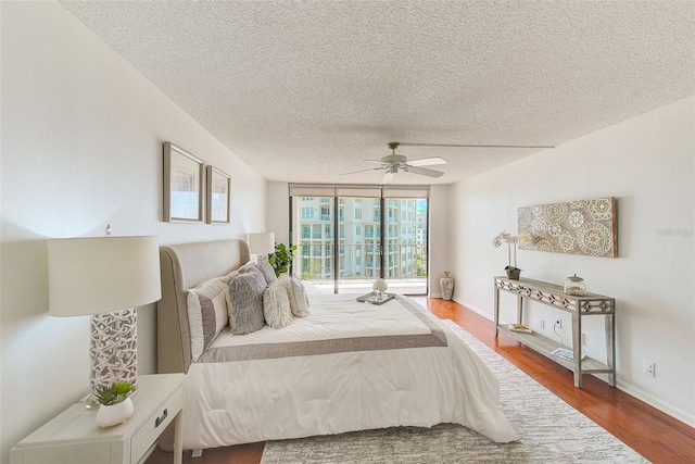 bedroom with floor to ceiling windows, hardwood / wood-style flooring, a textured ceiling, and ceiling fan