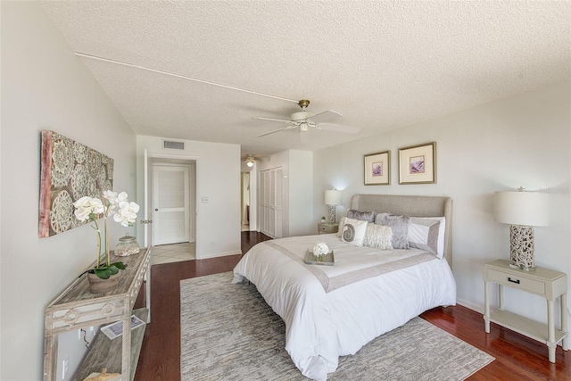 bedroom with a textured ceiling, ceiling fan, and dark wood-type flooring