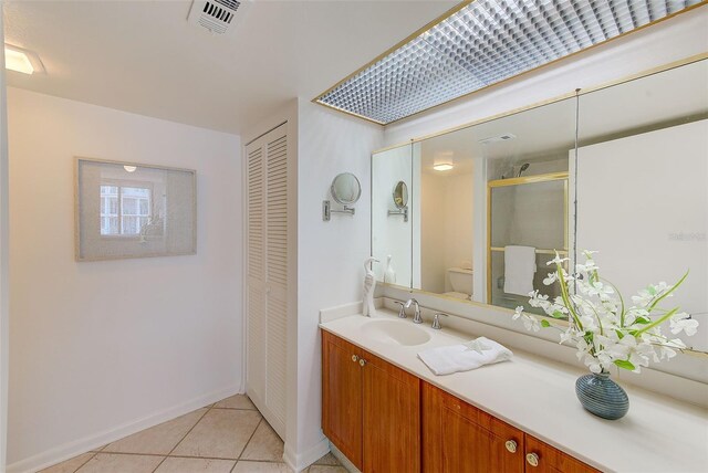 bathroom featuring toilet, tile patterned flooring, a shower with shower door, and vanity