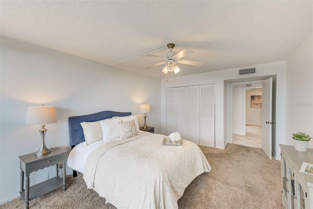 carpeted bedroom with a textured ceiling, ceiling fan, and a closet