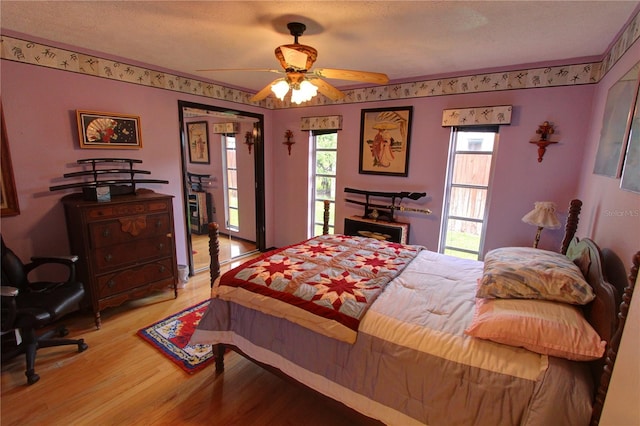 bedroom with light hardwood / wood-style flooring, multiple windows, a textured ceiling, and ceiling fan