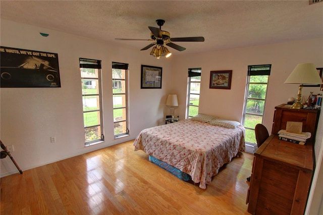 bedroom featuring light hardwood / wood-style flooring, multiple windows, and ceiling fan