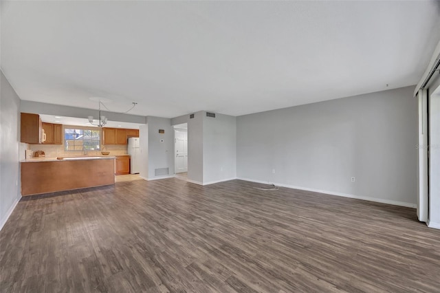 unfurnished living room with dark hardwood / wood-style flooring and an inviting chandelier